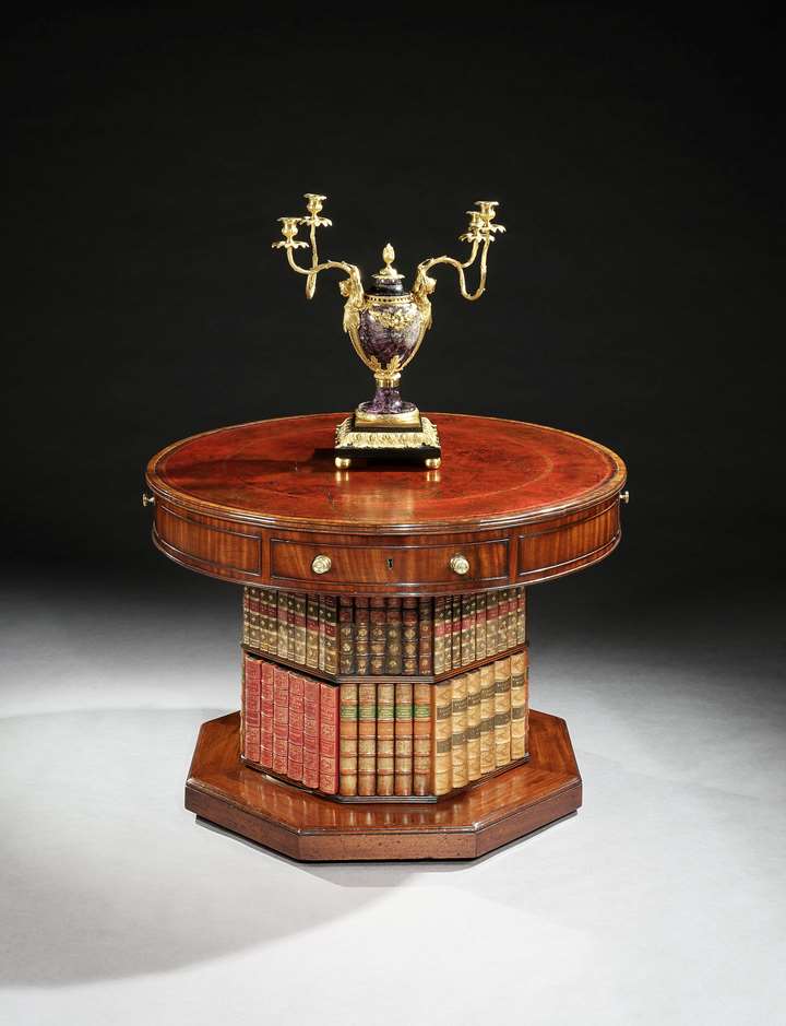 A regency mahogany revolving drum table on a bookcase pedestal